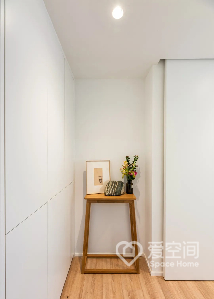 原入户处较窄，而且进门正对卫生间，给人感觉不是很好。设计师通过新建墙体，拓展了墙面，并将卫浴间门和大门进行了错位，显得门厅位置更加整洁宽敞。在进门左侧做了一整面墙的收纳柜，美观又能多储物。